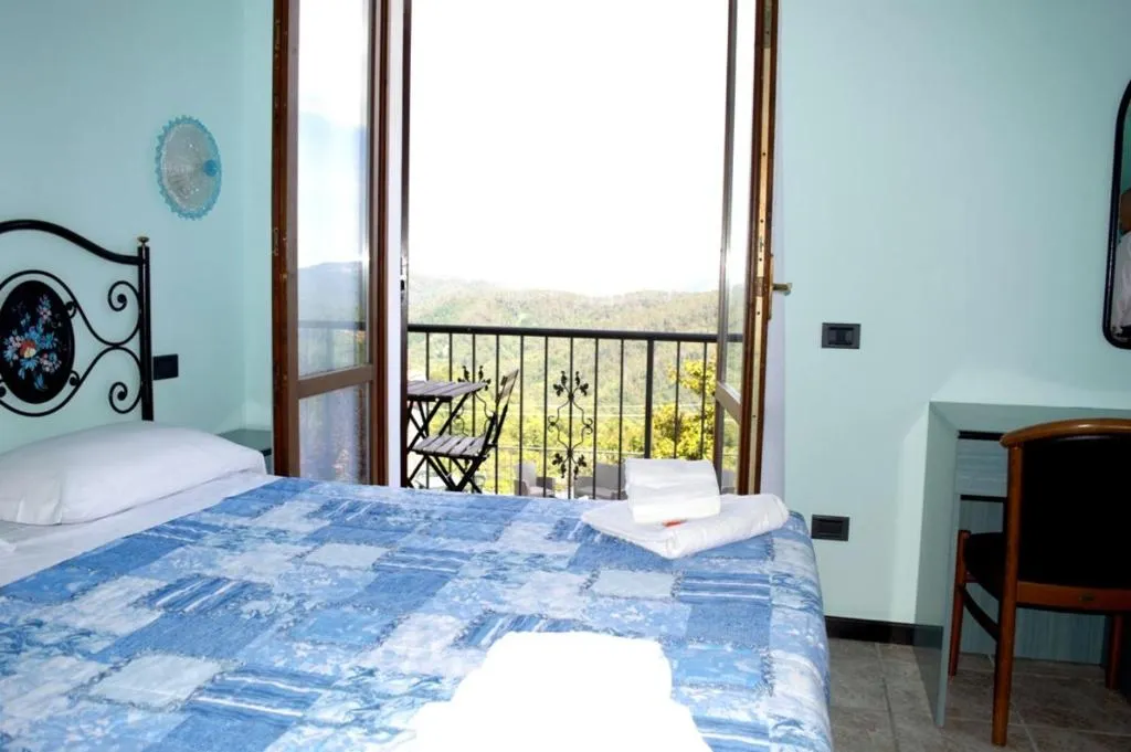 Camera con letto matrimoniale, copriletto azzurro e ampia porta finestra con vista