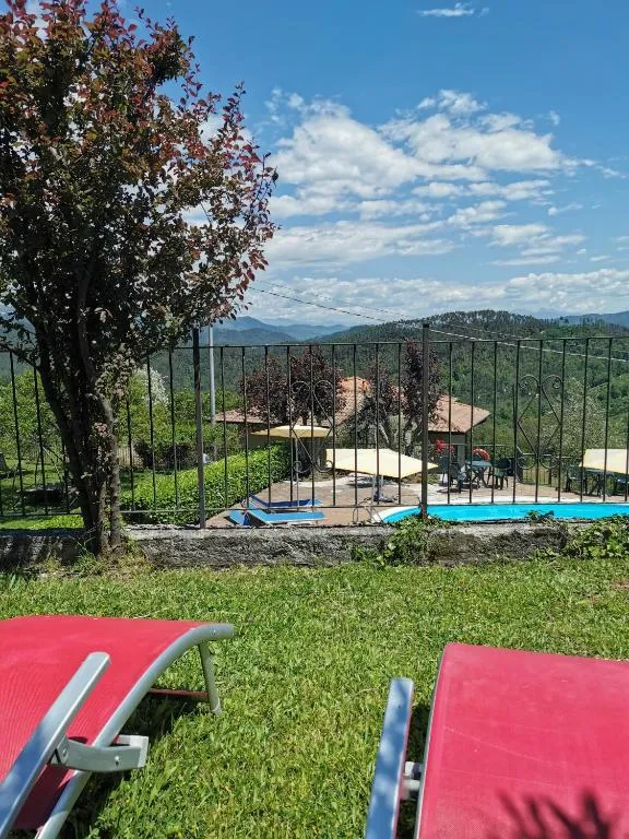 Vista sulla piscina e sulle colline da un giardino con lettini rossi