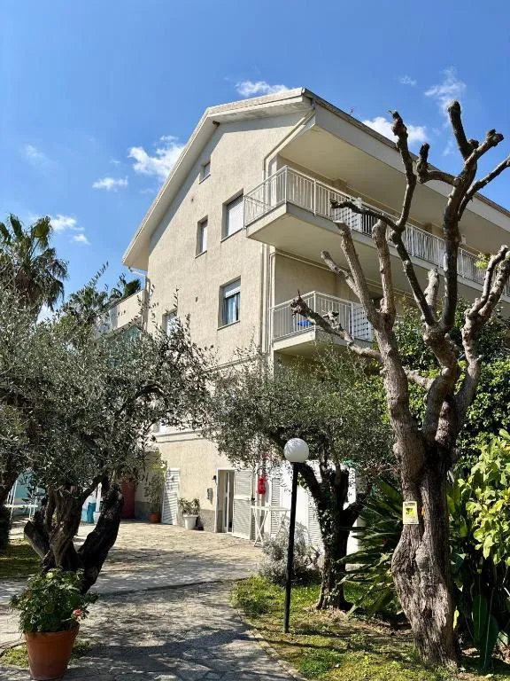 Esterno dell'edificio dell'hotel con balconi, ulivi e giardino