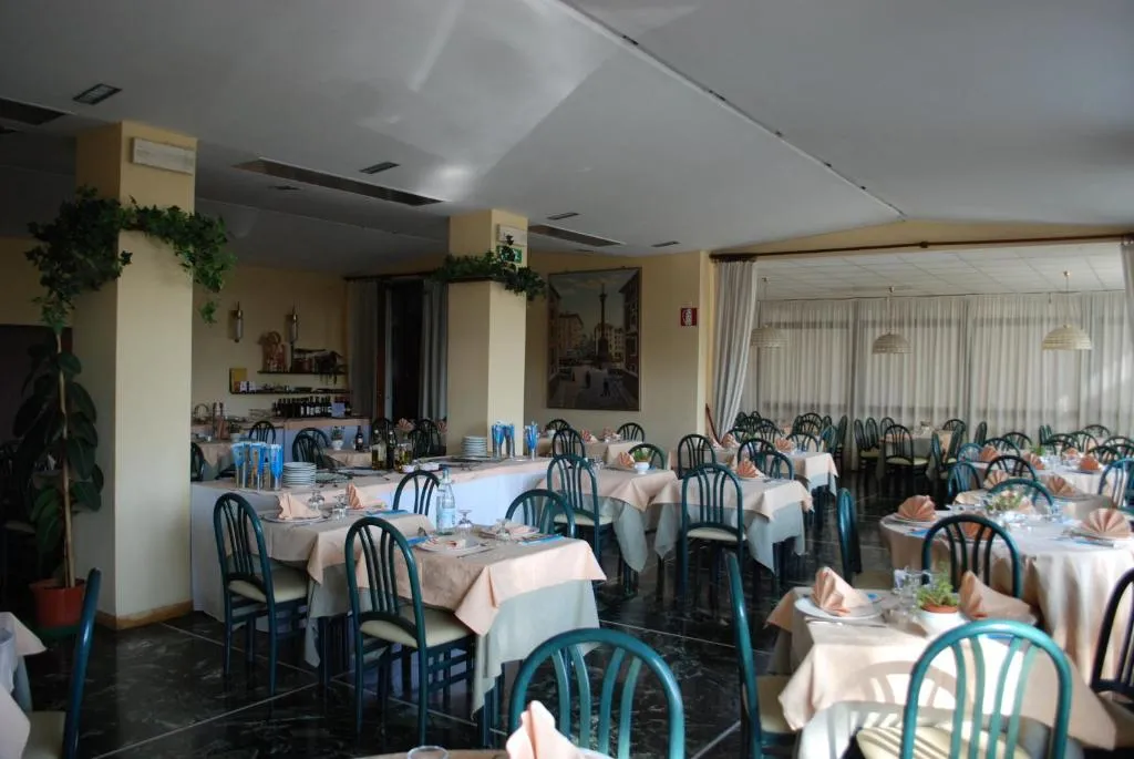 Sala ristorante con tavoli apparecchiati, sedie verdi e decorazioni con piante