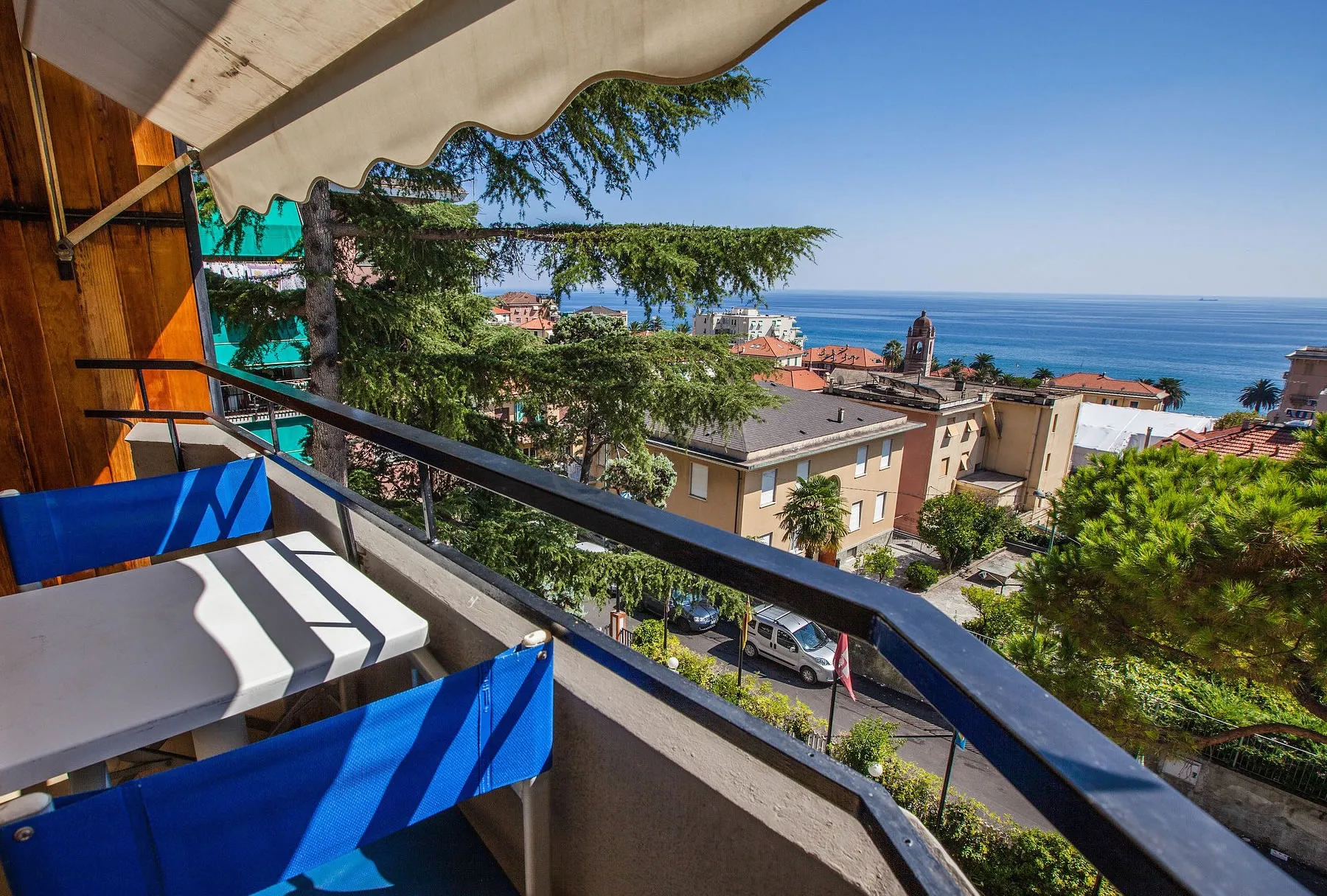 Balcone con sedie regista blu e vista sul mare e sul borgo tra i pini