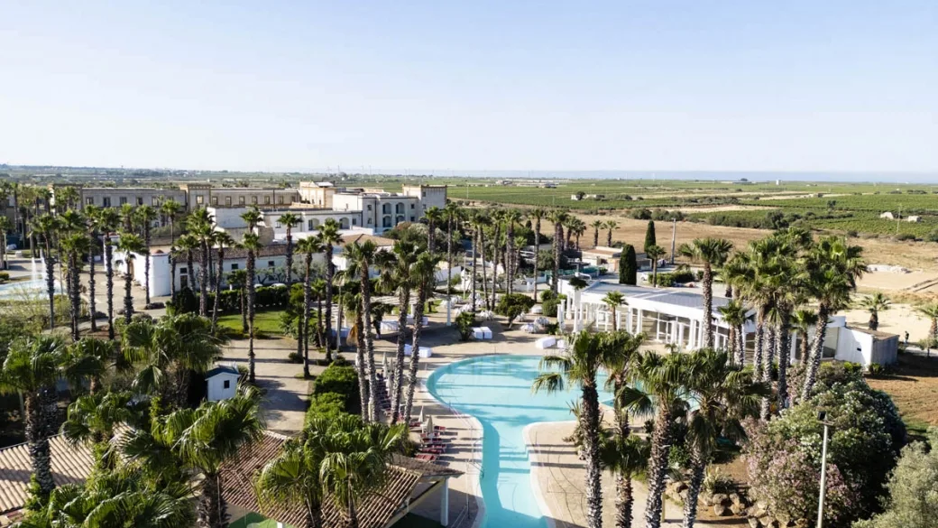 Veduta aerea del resort con piscina, palme e campagna circostante