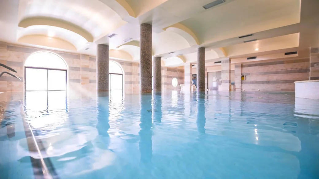 Piscina interna con colonne, soffitto a volte e pareti in marmo