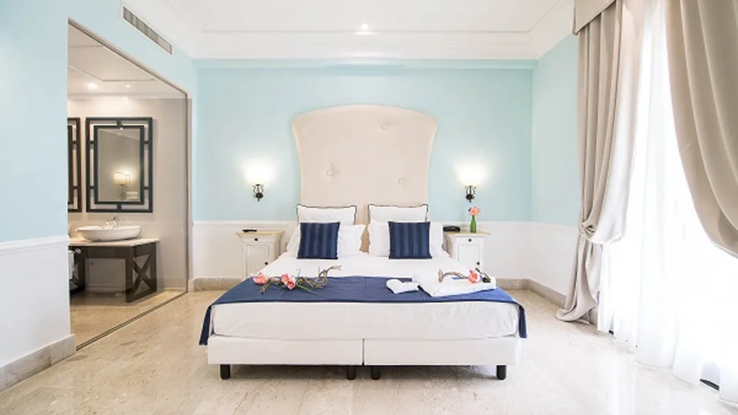 Camera elegante con letto matrimoniale, dettagli blu e bagno en-suite