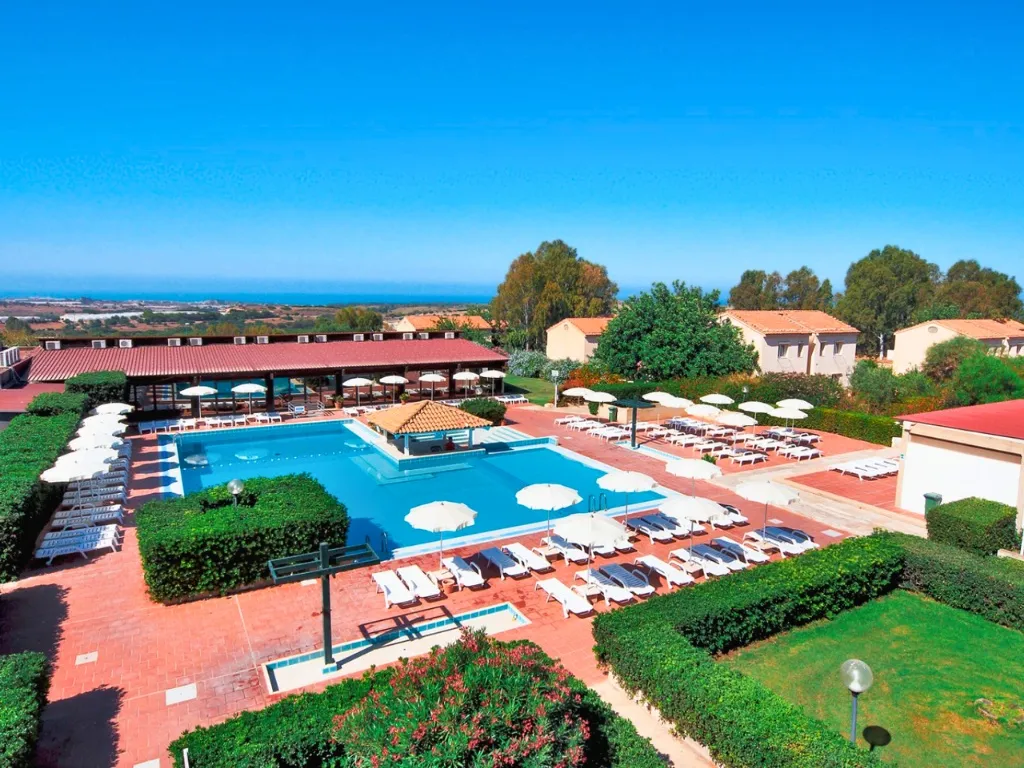 Vista panoramica della piscina circondata da lettini, siepi curate e vista sul mare