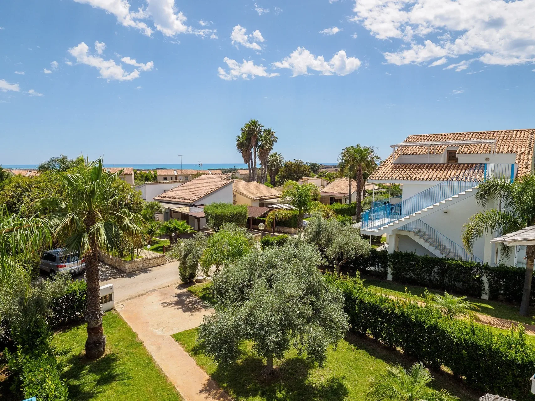 Villette del resort con tetti in tegole immerse tra palme e giardini con vista mare