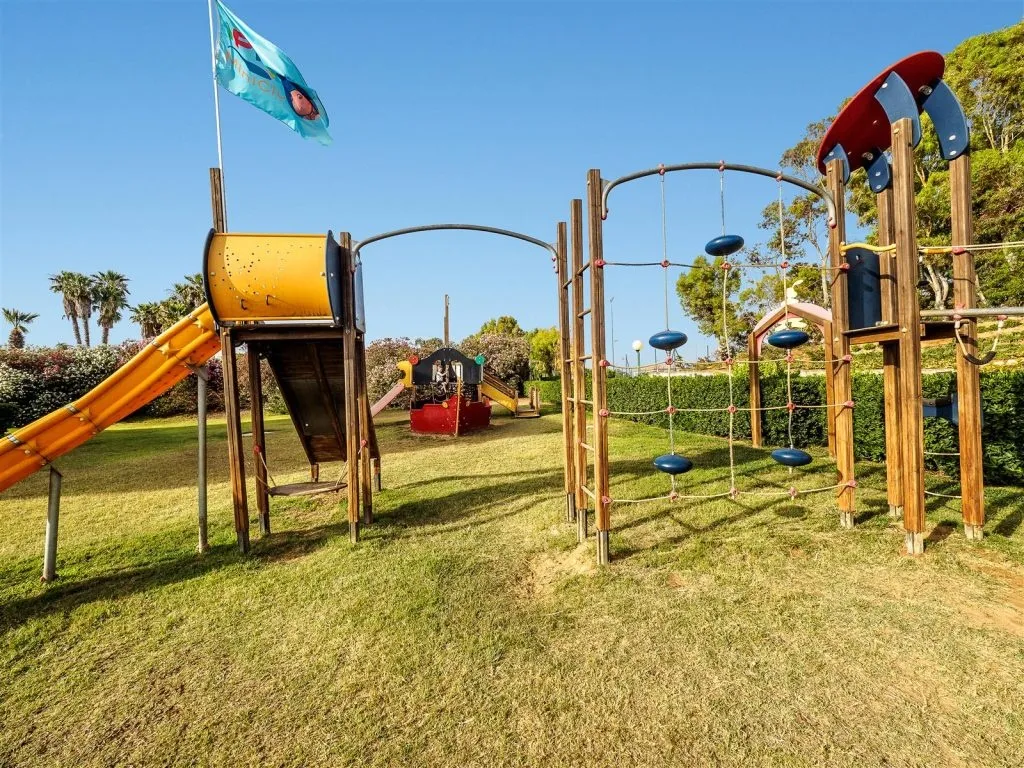 Parco giochi per bambini con scivoli e percorso di arrampicata su prato verde