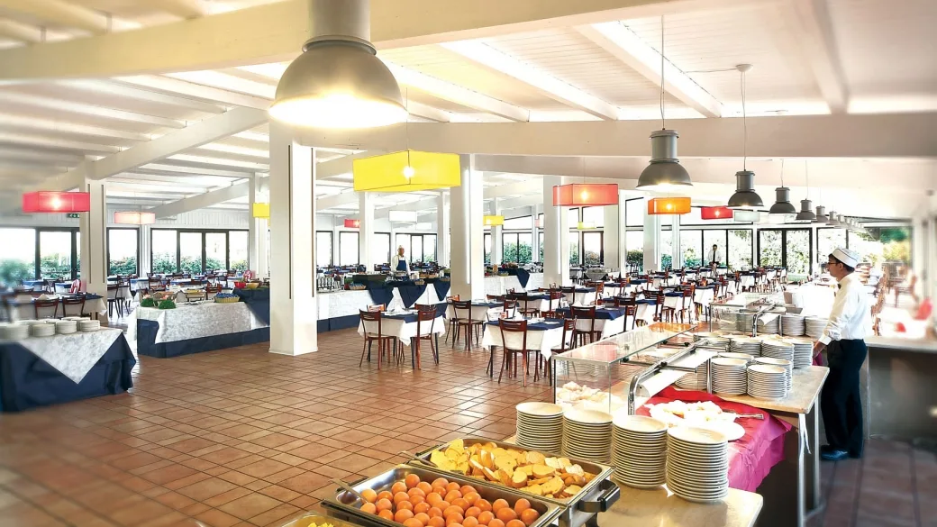 Sala ristorante a buffet luminosa con tavoli apparecchiati e ampie vetrate