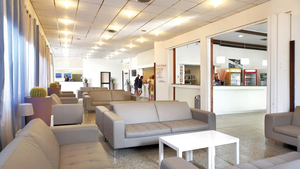 Area lounge dell'hotel con divani in pelle, reception e bar sullo sfondo