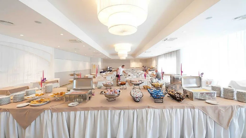 Sala colazioni con buffet allestito, tovaglie bianche e lampadari moderni