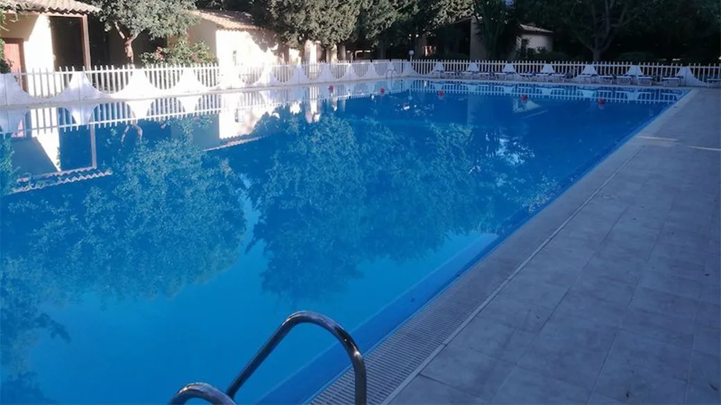 Vista della piscina esterna con acqua azzurra e bordo piastrellato