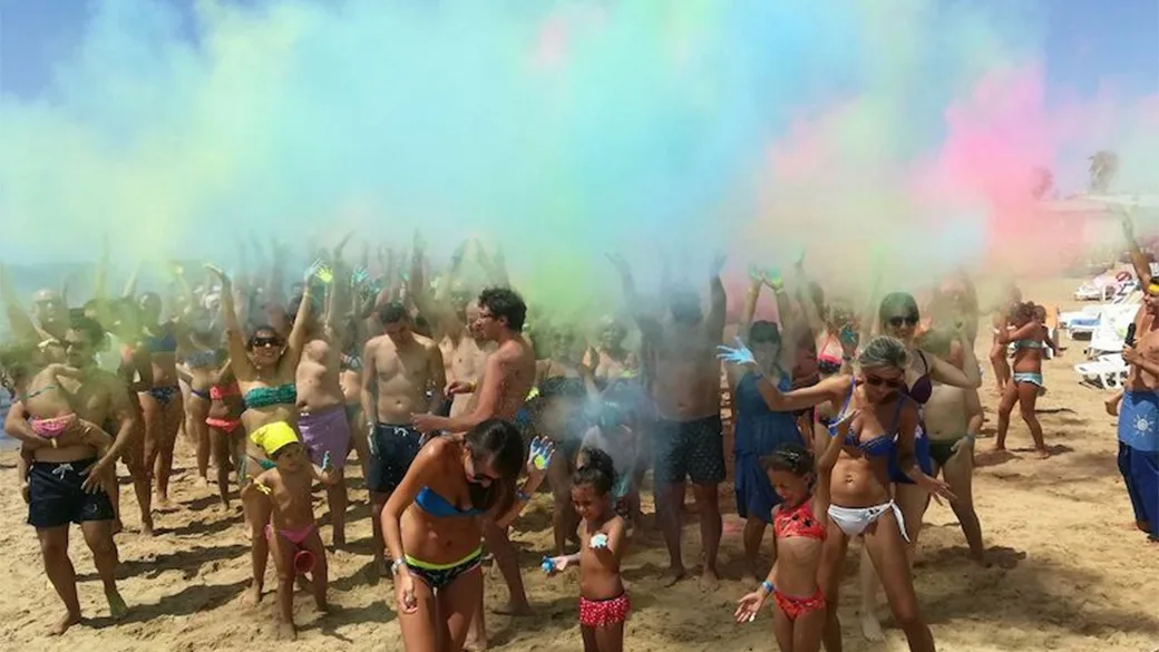 Animazione in spiaggia con persone e nuvole di polveri colorate