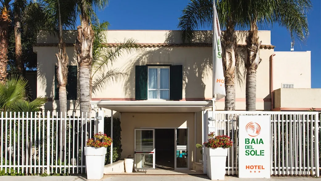 Ingresso dell'Hotel Baia del Sole con palme e cancello bianco