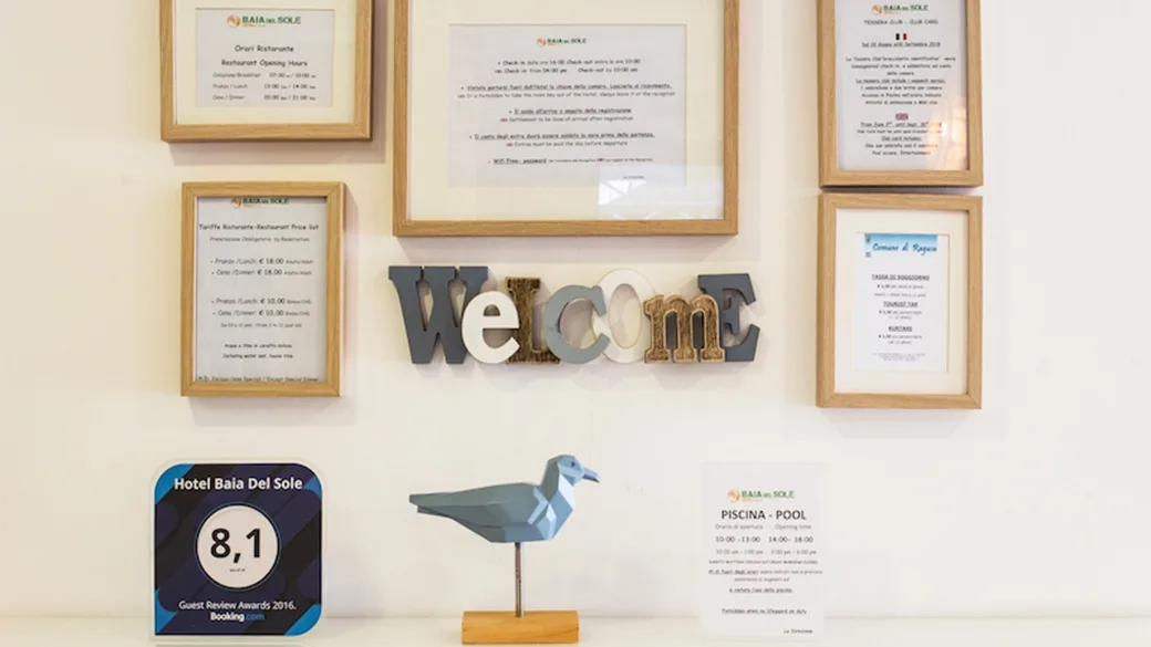 Parete della reception con avvisi, scritta Welcome e premio ospiti
