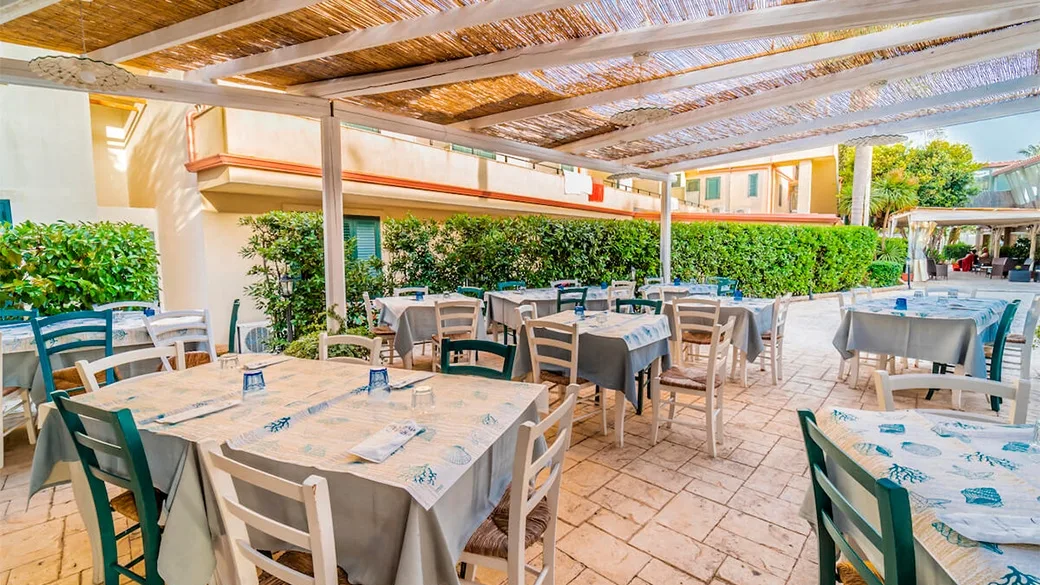 Ristorante esterno coperto da pergola in canne con tavoli apparecchiati