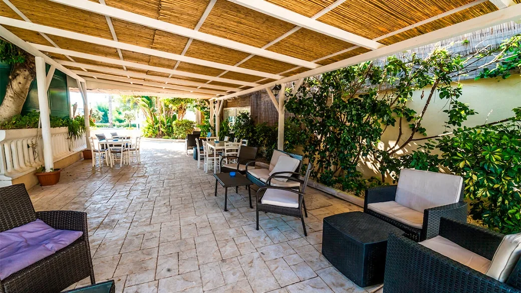 Veranda con pergola in canne, divani in vimini e tavoli da pranzo