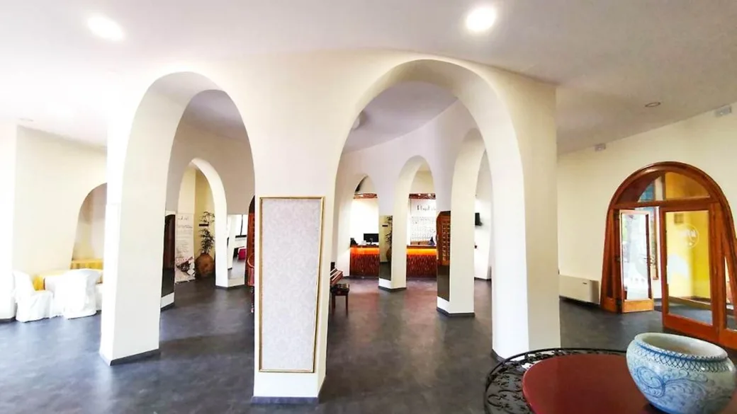 Hall dell'hotel con archi bianchi, reception e arredi