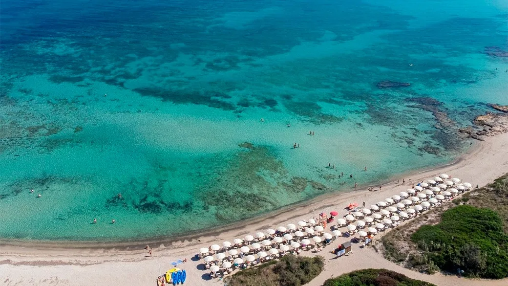 Veduta aerea della spiaggia sabbiosa con ombrelloni e mare cristallino turchese