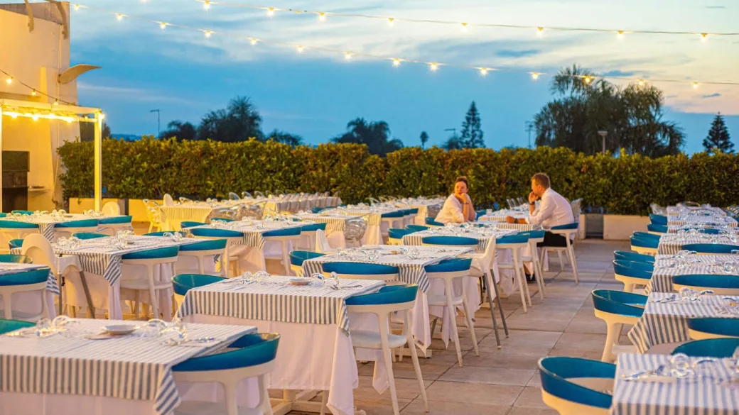 Ristorante all'aperto al tramonto con tavoli apparecchiati e luci decorative