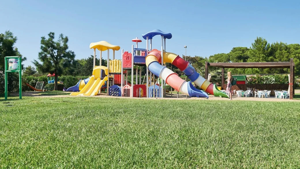 Parco giochi per bambini con scivoli colorati su prato verde