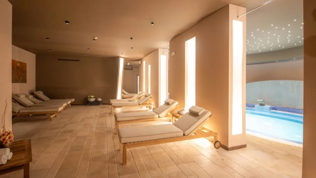 Zona relax della spa con lettini in legno e piscina interna