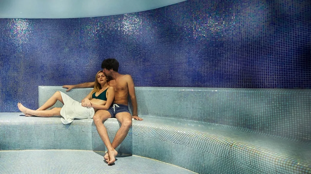 Coppia che si rilassa nel bagno turco della spa con mosaico blu
