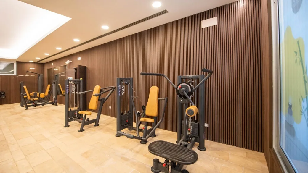 Palestra del resort con macchinari per il fitness e parete in legno