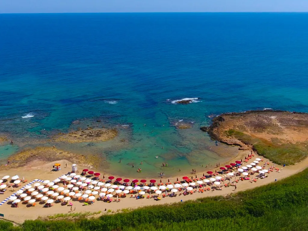 Veduta aerea di spiaggia con ombrelloni colorati e mare azzurro cristallino