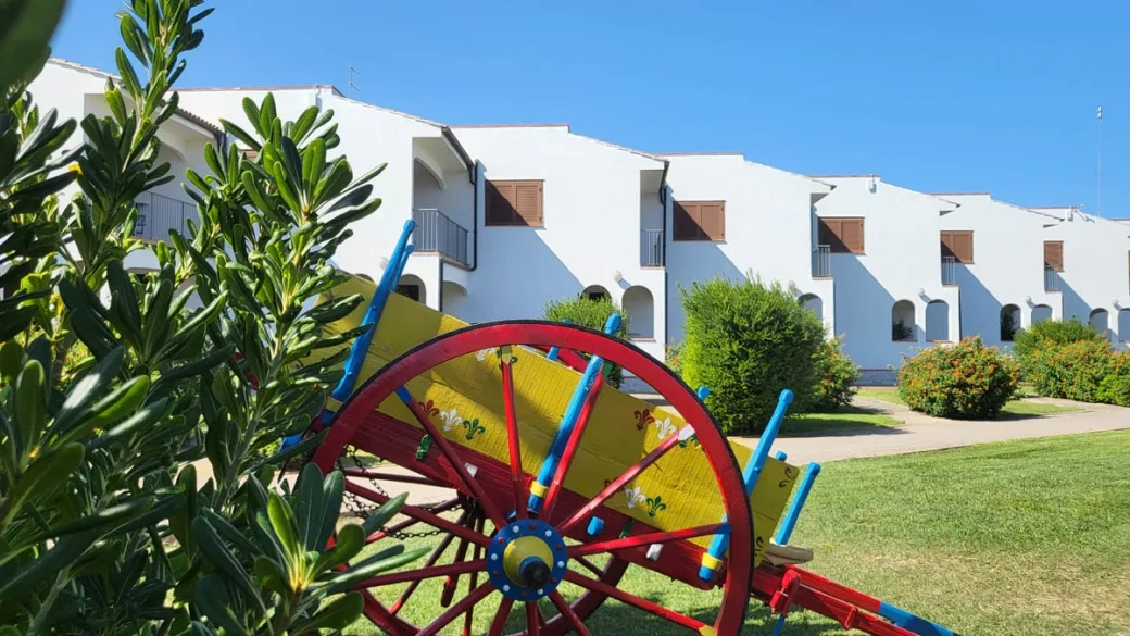 Carretto siciliano decorato in giardino davanti a edifici bianchi del resort