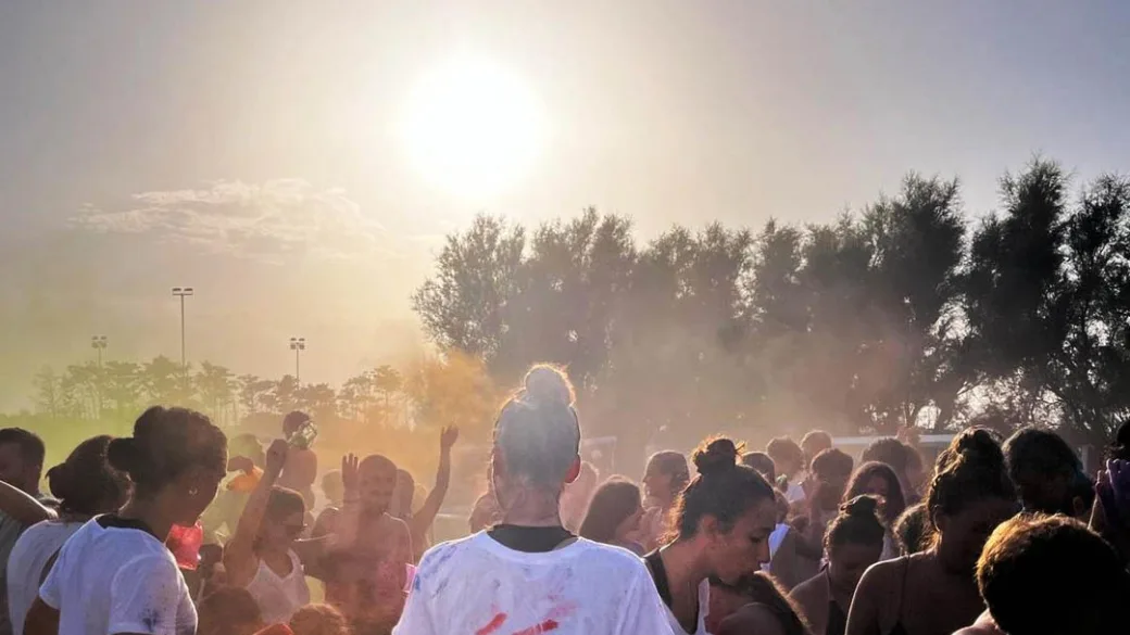 Festa all'aperto con folla di persone durante evento animazione al tramonto
