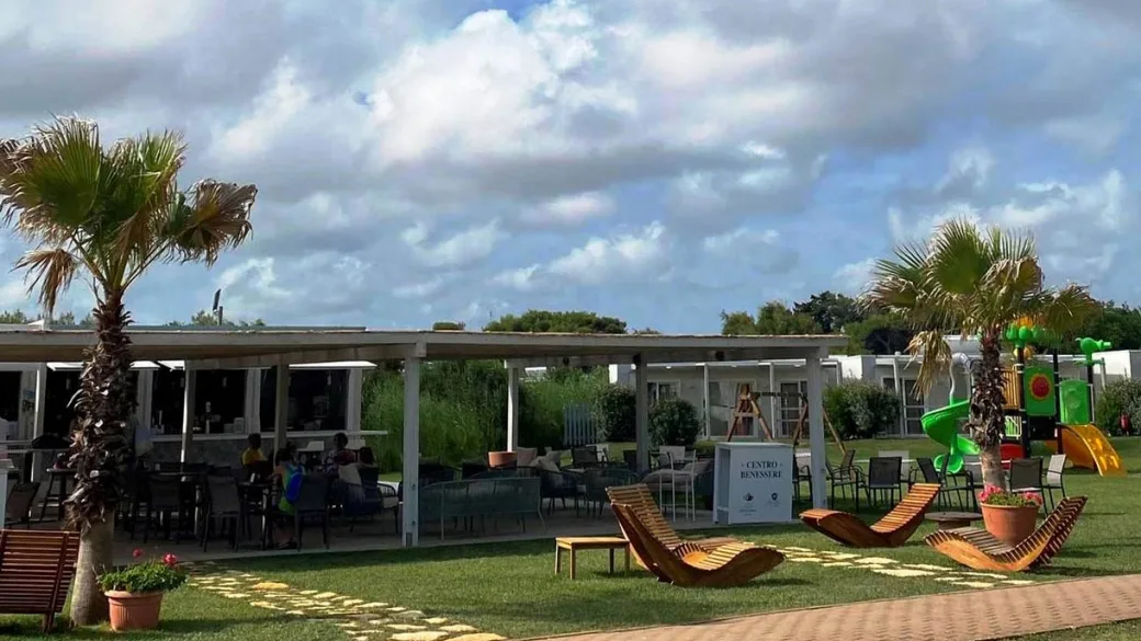 Area lounge esterna con divani, palme, parco giochi e zona benessere del resort