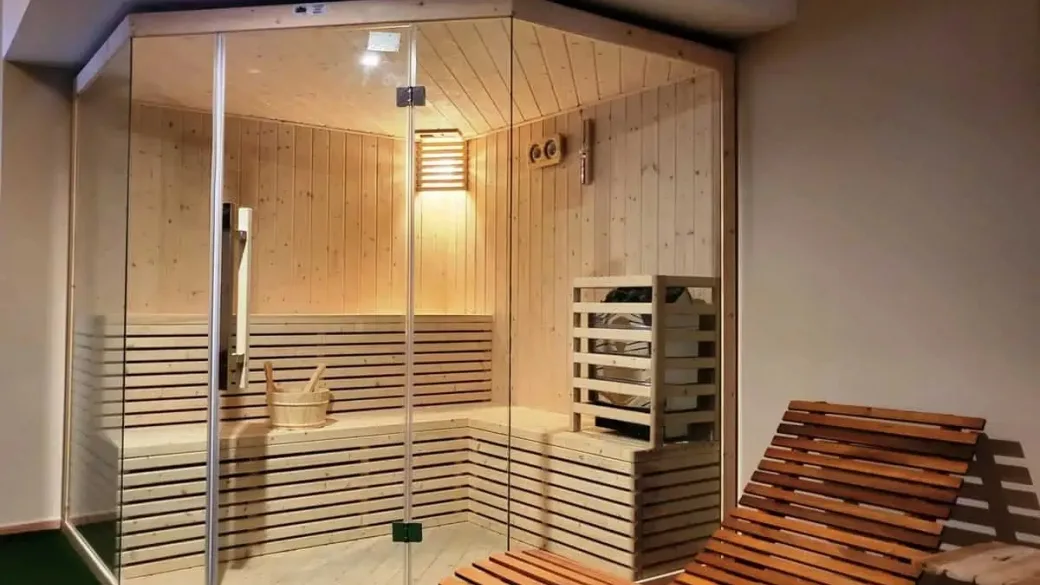 Sauna finlandese in legno con pareti vetrate e lettino relax accanto