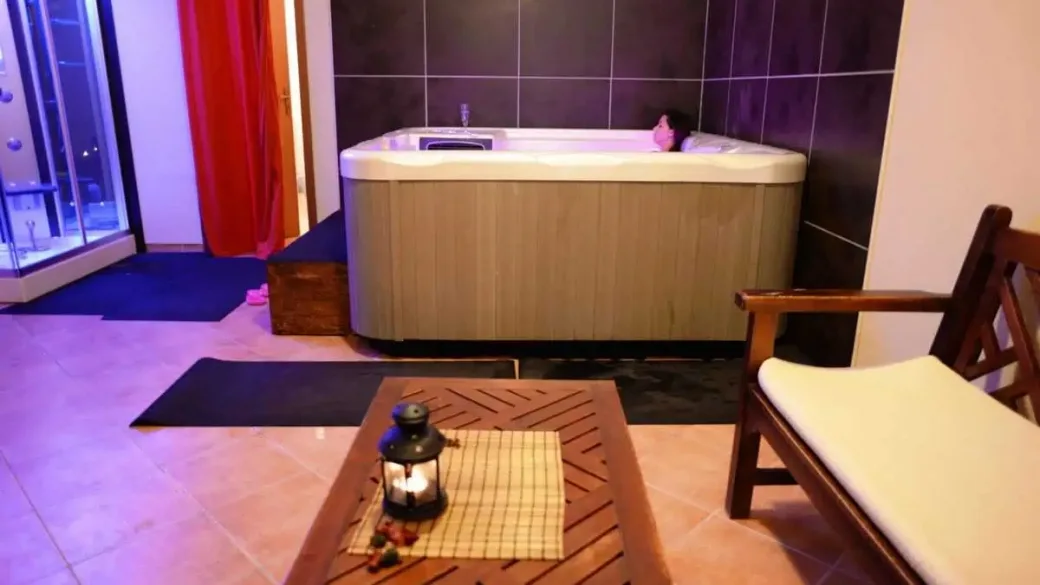 Zona benessere con vasca idromassaggio, poltrona in legno e atmosfera soffusa
