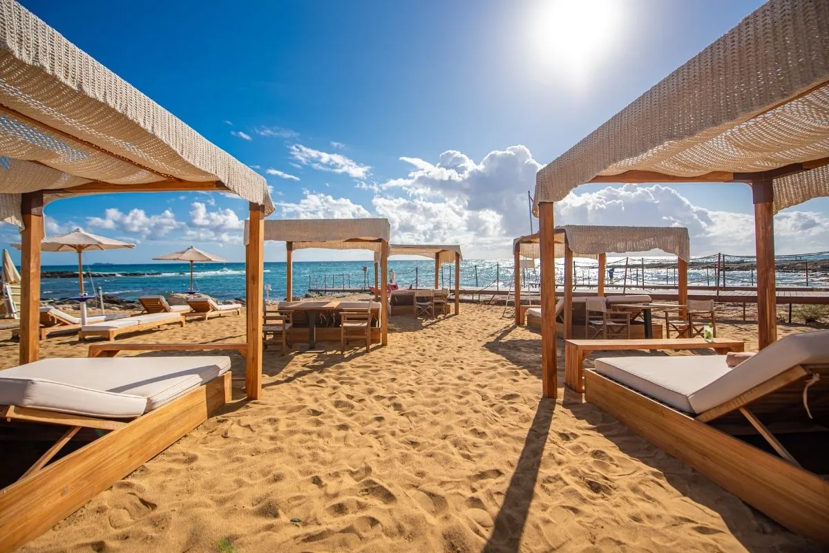 Gazebo in legno con lettini imbottiti sulla spiaggia al tramonto
