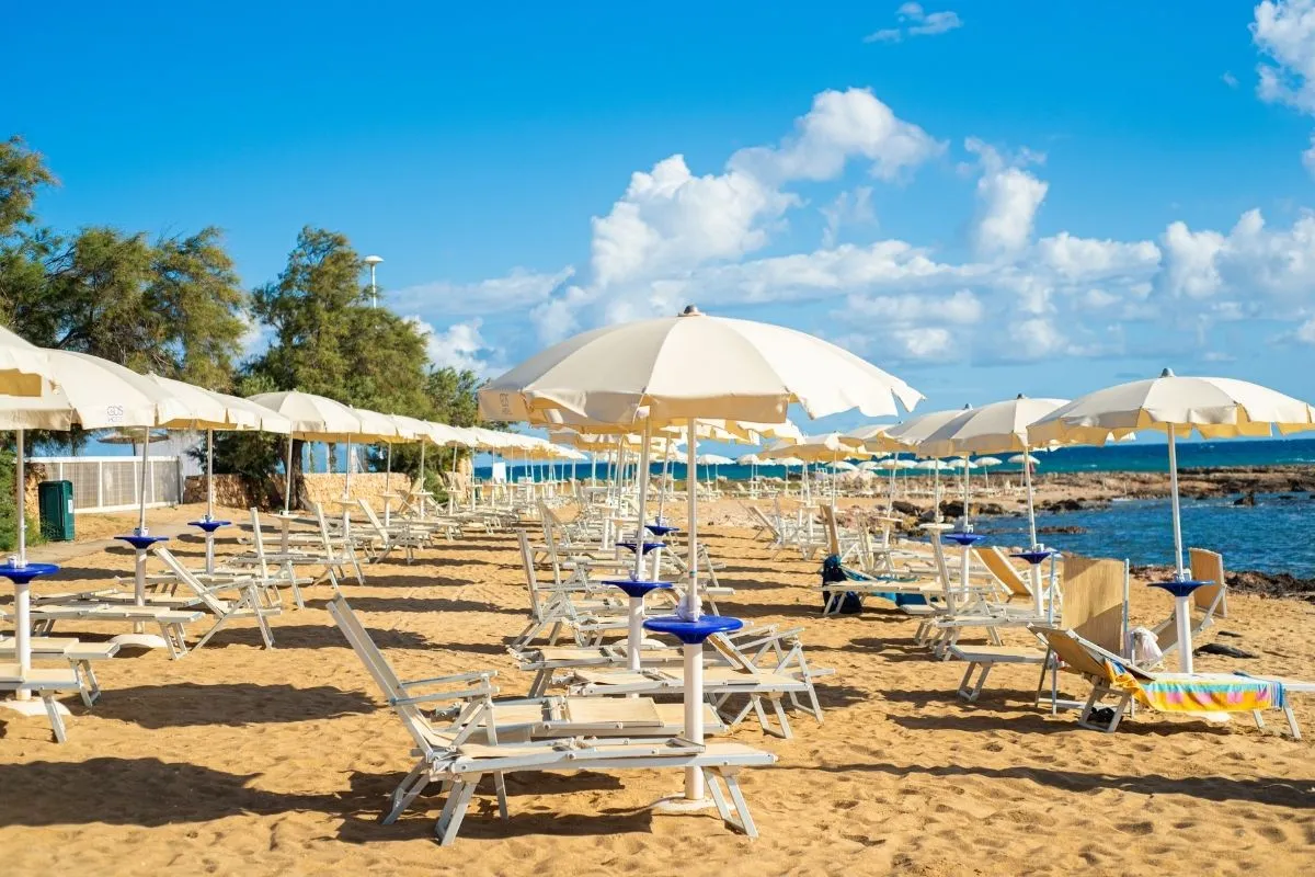 Spiaggia sabbiosa con lettini e ombrelloni bianchi vista mare