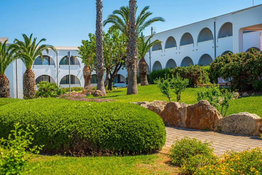 Giardino curato con palme, siepi e edifici bianchi ad archi