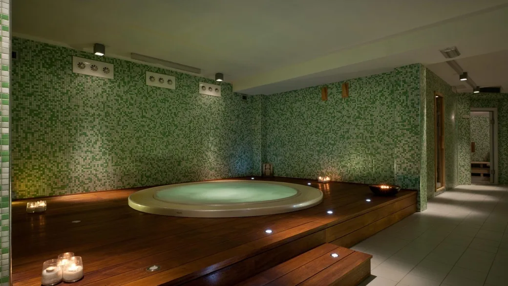 Vasca idromassaggio interna con mosaico verde e candele