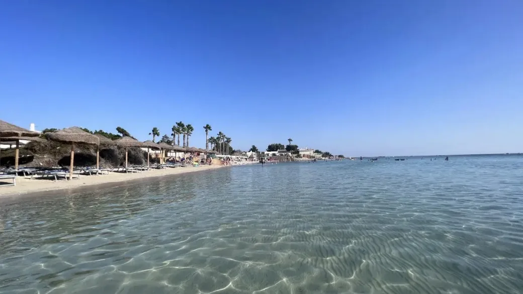 Spiaggia sabbiosa con mare cristallino e ombrelloni in lontananza