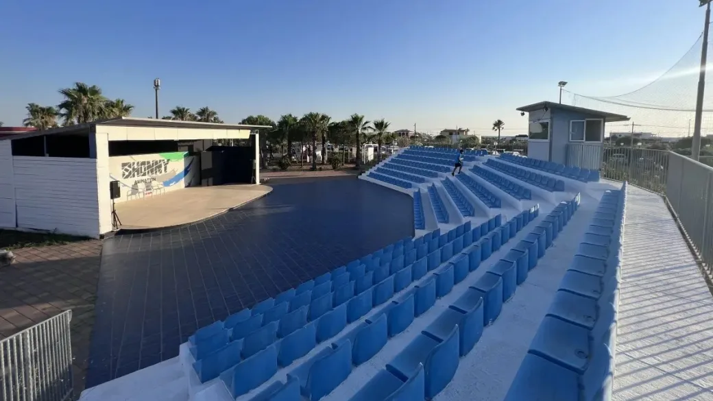 Anfiteatro all'aperto con sedute blu e palco per animazione
