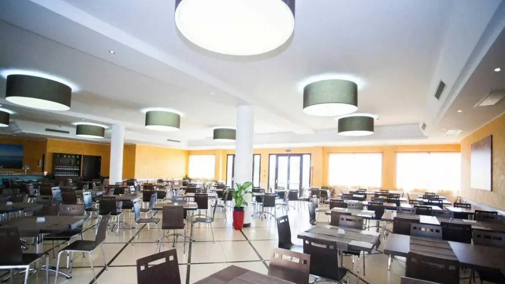 Ampia sala ristorante luminosa con tavoli e pareti gialle