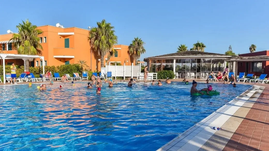 Piscina con bagnanti e palazzine arancioni sullo sfondo