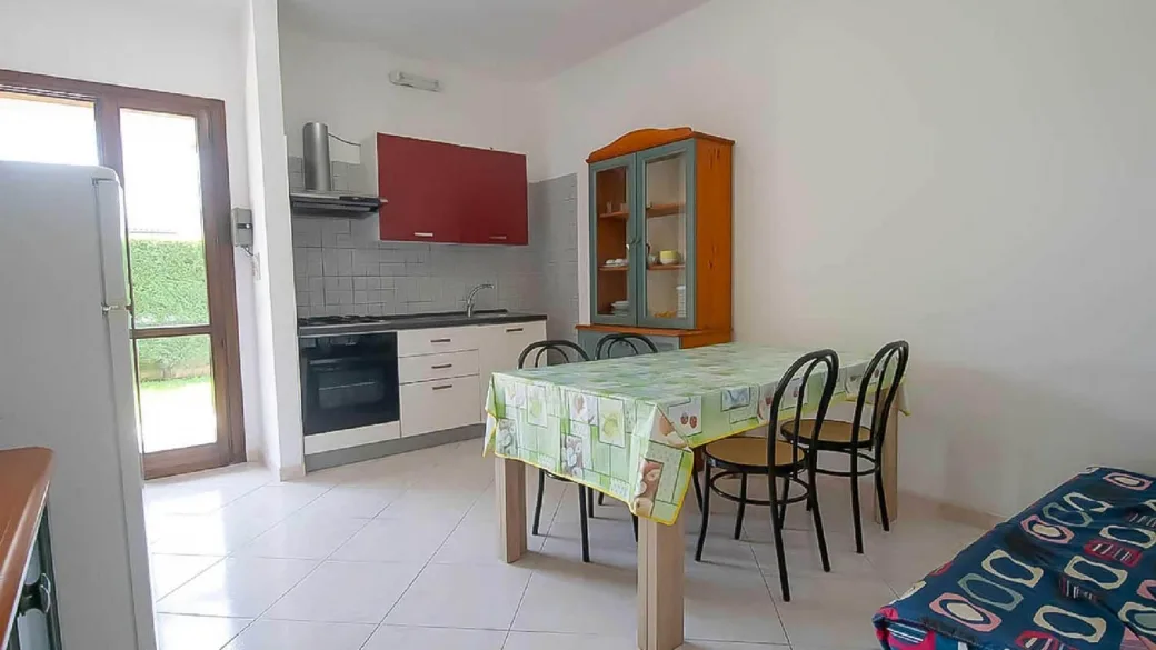Cucina con angolo cottura, tavolo da pranzo e uscita sul giardino