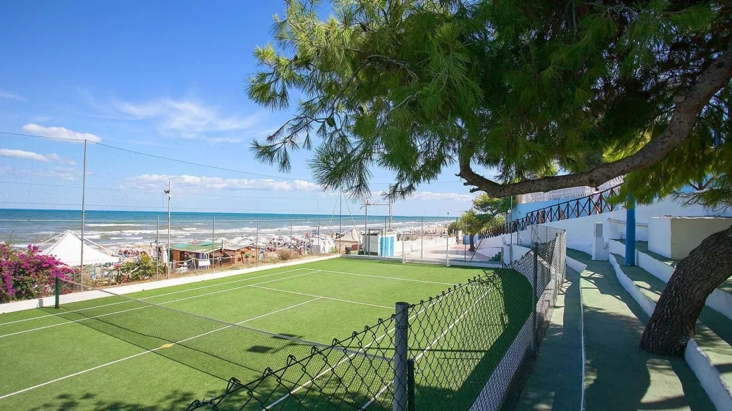 Campo da tennis in erba sintetica con vista sulla spiaggia e sul mare