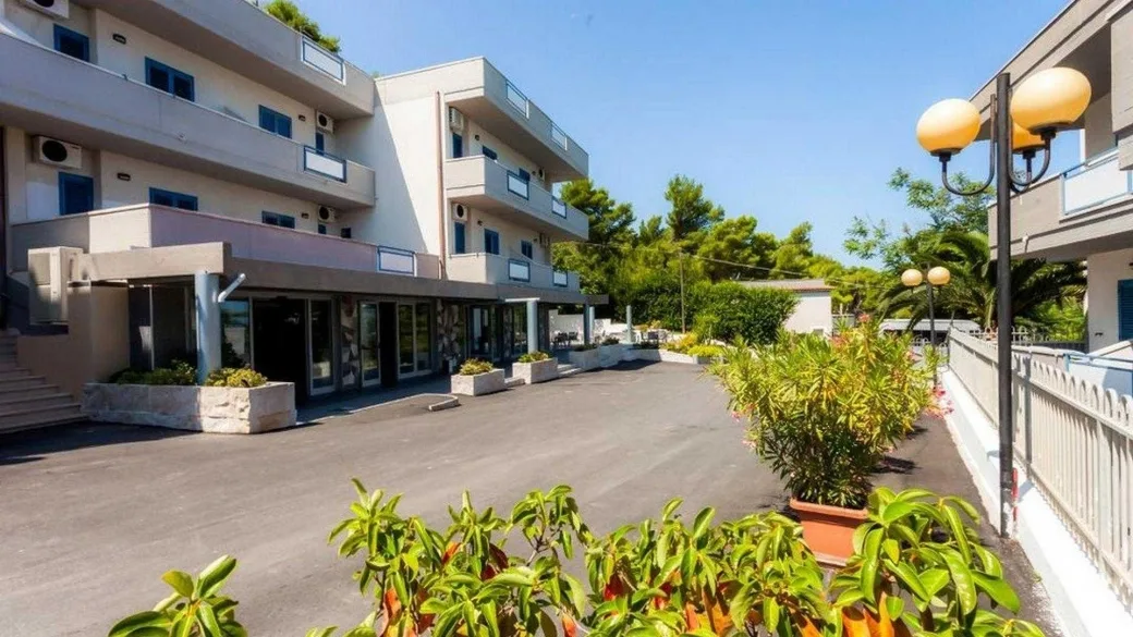 Esterno della struttura con ingresso, balconi e piazzale con piante