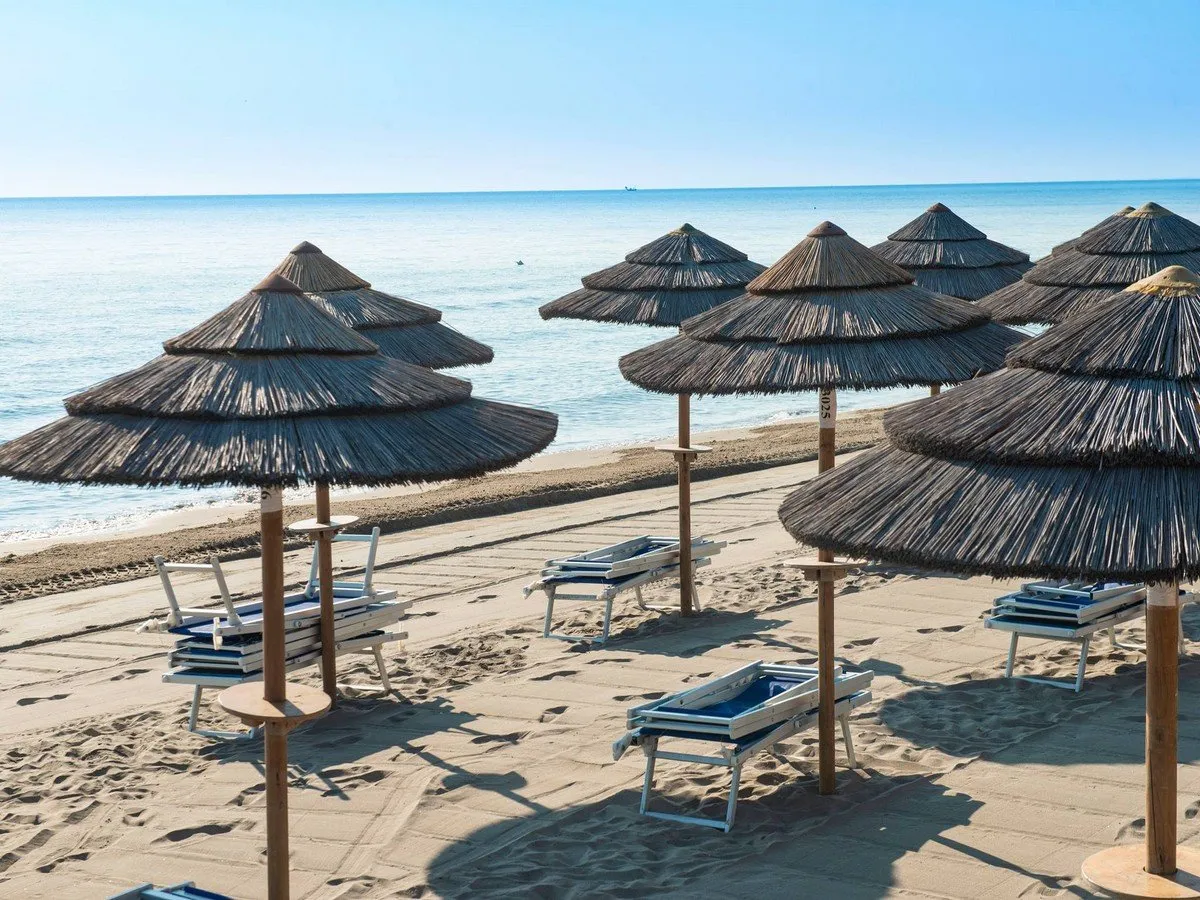 Ombrelloni in paglia e lettini sulla spiaggia con vista sul mare