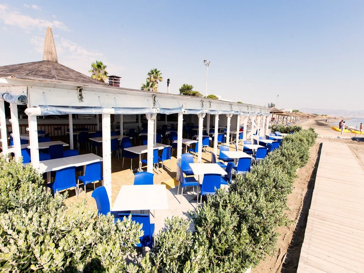 Terrazza ristorante sulla spiaggia con tavoli e sedie blu affacciata sul mare