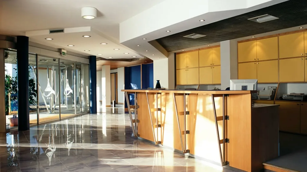 Reception dell'hotel con bancone in legno e pavimento lucido