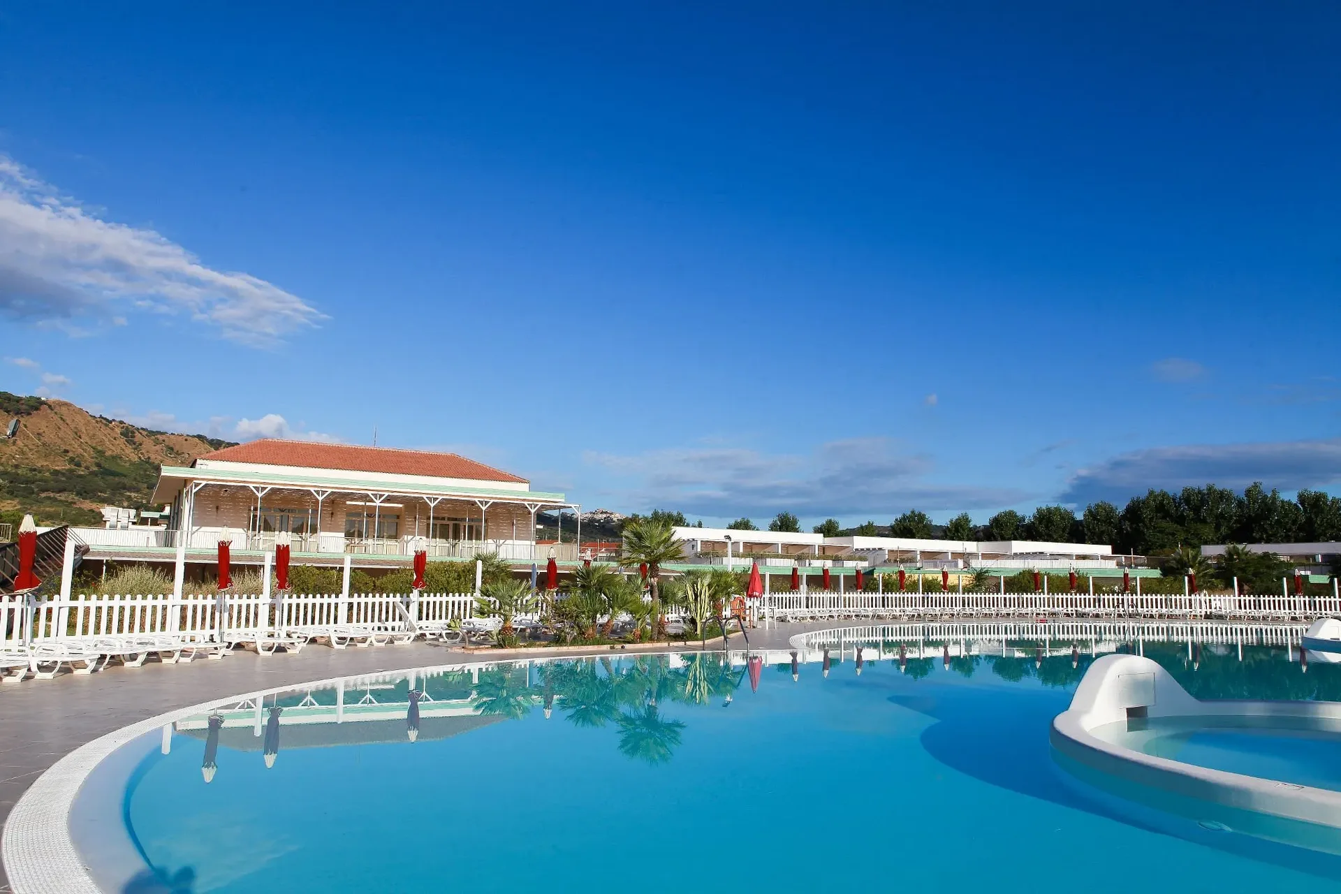 Grande piscina del resort con edificio principale e montagna sullo sfondo