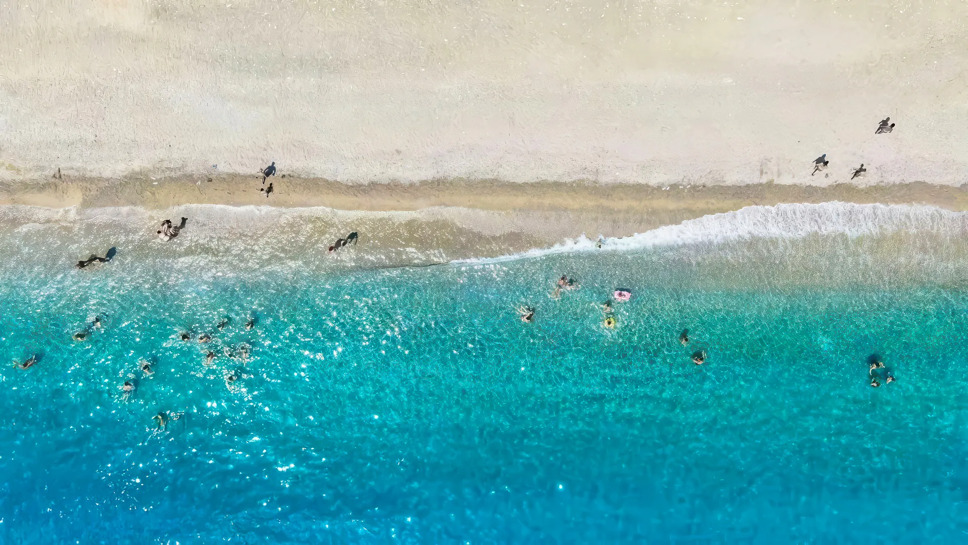 Vista dall'alto di bagnanti nelle acque turchesi sulla spiaggia