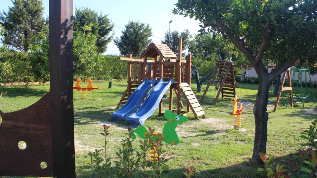 Parco giochi per bambini con scivoli blu e altalene nel verde